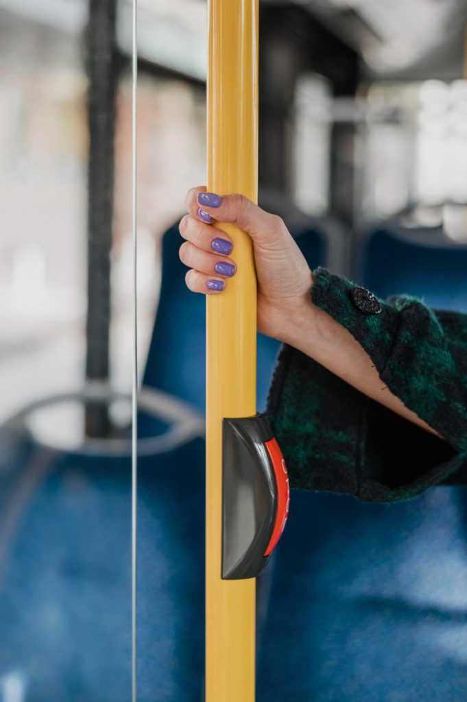 women holding her hand on bus pole