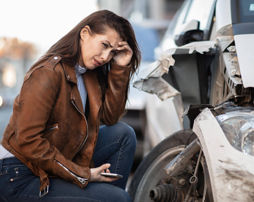 Young Woman Sitting Next to Her Wrecked Car
